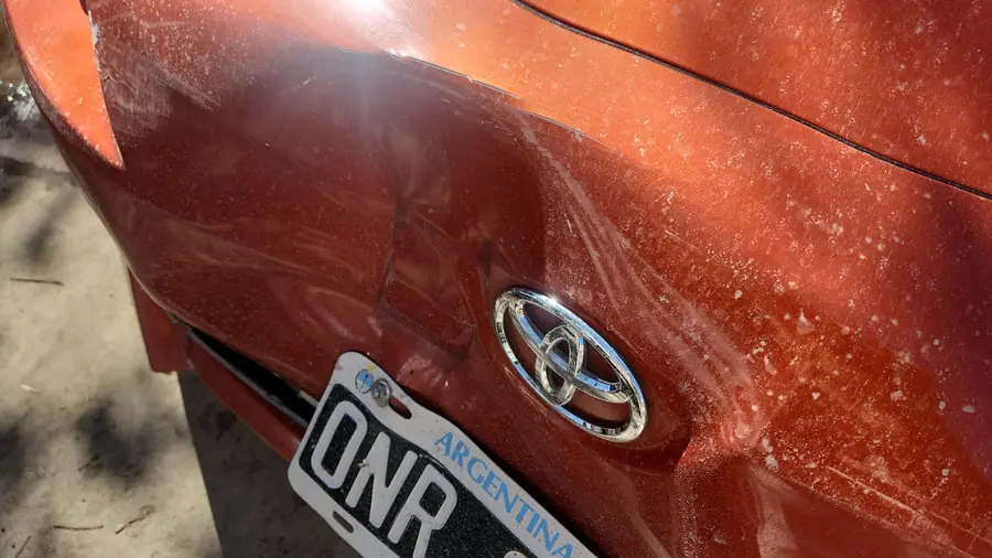 Detalle del daño en la carrocería trasera junto al emblema y la patente.