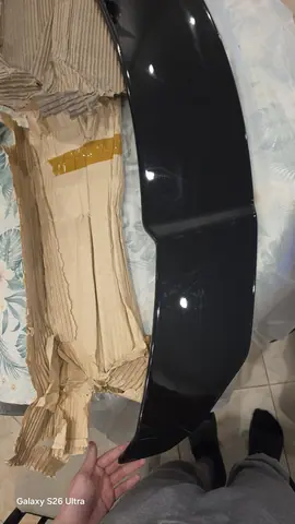El alerón negro recién sacado de su caja de cartón, sobre el piso.