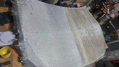 Tejido de fibra de vidrio a medio impregnar de resina sobre la superficie del capó.