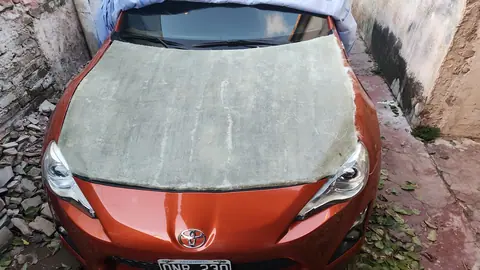 La pieza cruda de fibra de vidrio apoyada sobre el frente del auto naranja para probar el calce.