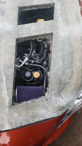 Detalle de una toma de aire con el filtro de aire cónico violeta visible debajo.