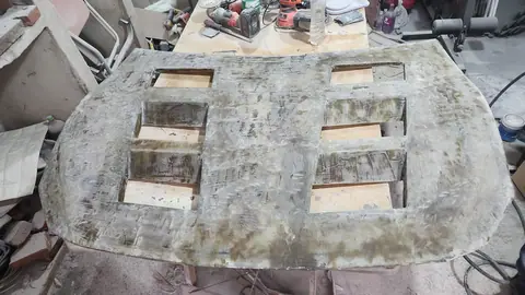 El capó masillado y lijado sobre la mesa de trabajo, con manchas de masilla.