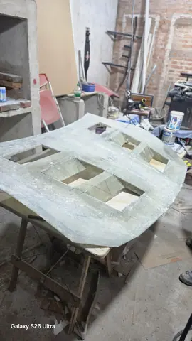 El capó lijado sobre caballetes de madera en el taller.