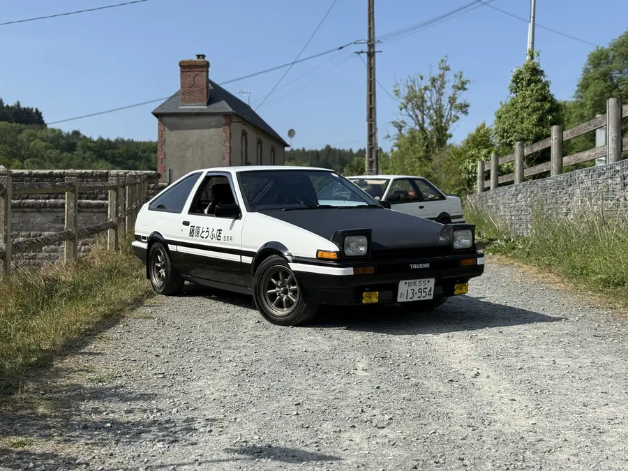 Un Toyota Sprinter Trueno AE86 de tres puertas pintado en el esquema blanco y negro conocido como panda.