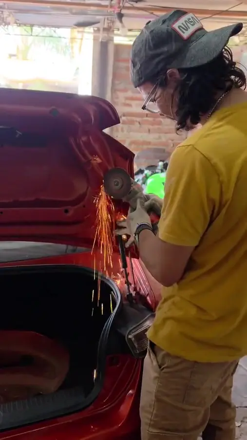 Fotograma del video: la amoladora cortando la chapa de la tapa del baúl, con chispas saltando.