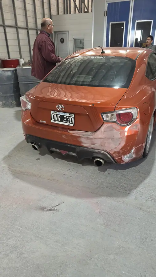 La cola del Toyota 86 con el paragolpes trasero partido y la pintura saltada, en el taller antes de repararse.